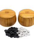 Go Bowls & Stones Set with black and white ceramic go stones laying in front of closed bamboo bowls