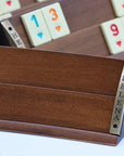 Close-up of luxury Rummikub set showing curved solid beech wood rack wood grain with racks holding heat-treated melamine tiles in the background in a soft focus.