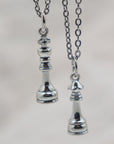 Silver pendant necklace with a King or Queen chess piece charm in antique silver-tone finish link chain.
