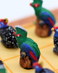 Close up of African Bird Noughts & Crosses resin game set with hand-painted birds showcasing Loerie & Guineafowl pieces