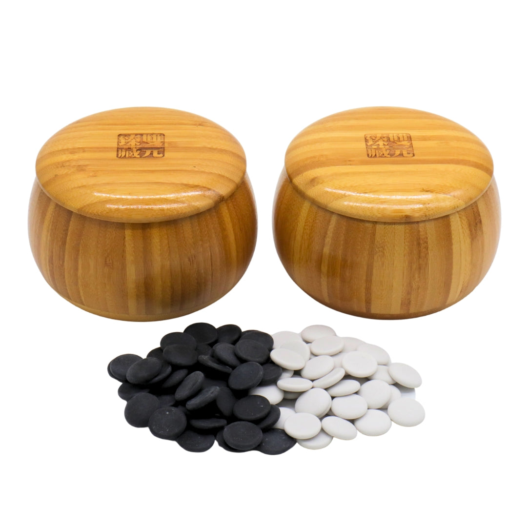 Go Bowls &amp; Stones Set with black and white ceramic go stones laying in front of closed bamboo bowls