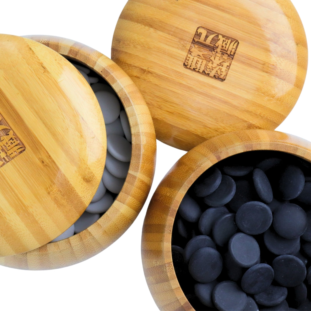 Top view of Go Bowls &amp; Stones Set with lids lifted off 2 bamboo bowls showing black and white ceramic go stones